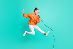 Full size profile side photo of young crazy screaming girl jumping singing in microphone isolated on turquoise color background