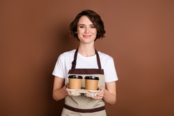 Portrait of charming cheerful girl hands hold coffee cups box look camera isolated on brown color background