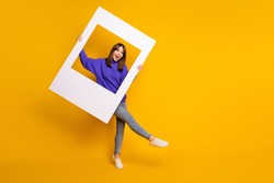 Photo of adorable charming young woman wear purple sweater dancing holding white photo frame isolated orange color background