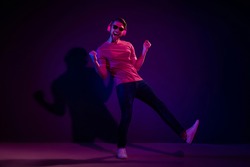 Full length body size view of attractive cheerful carefree guy listening sound dancing isolated over dark neon violet color background
