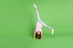 Full body photo of young little girl stand on hand acrobat sporty training isolated over green color background