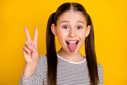 Photo of young girl happy positive smile show peace cool v-sign grimace tongue-out isolated over yellow color background