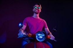 Portrait of attractive cheerful guy riding bike traveling pastime tour isolated over dark neon purple color background