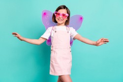 Photo of adorable cute school girl wear pink overall glasses wings smiling dancing isolated teal color background
