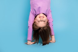 Photo portrait little girl doing handstand upside down isolated pastel blue color background