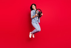 Full length body size view of pretty cheerful girl jumping holding steering wheel way trip isolated over bright red color background