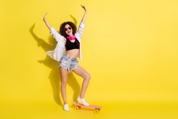 Full length body size photo of female skateboarder headphones sunglass riding longboard cheerful happy isolated vibrant color background