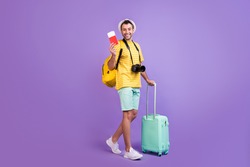 Full size profile side photo of young man happy positive smile travel abroad tickets bag isolated over violet color background
