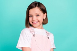 Photo of cheerful shiny schoolgirl dressed pink overall smiling isolated turquoise color background