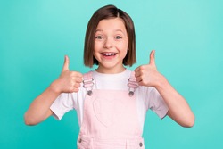 Photo of cheerful happy young small girl make fingers thumbs up smile recommend isolated on teal color background
