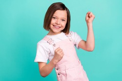 Photo of happy charming nice little girl winner raise fists smile isolated on pastel teal color background