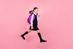 Full length body size photo schoolgirl jumping keeping backpack walking to school isolated pastel pink color background