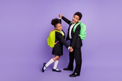 Photo of two african people schoolchildren dance hold hands wear rucksack uniform isolated violet color background