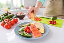Photo of mature woman squeeze lemon juice dish cook gourmet salmon vegetables diet cafe delicious food indoors