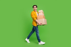 Full size photo of young handsome good mood man go walk hold carton boxes move new house isolated on green color background