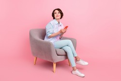 Full length body size photo woman sitting browsing internet on smartphone looking copyspace isolated pastel pink color background