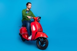 Full size photo of serious cool confident peaceful guy ride moped traveling road isolated on blue color background