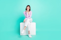 Full length body size photo woman sitting wearing stylish clothes touching chin isolated bright teal color background