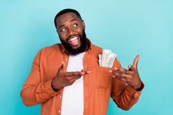 Photo of young afro man happy positive smile rich businessman cash money dollars look empty space isolated over teal color background
