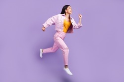 Full length profile photo of funny young brunette lady run wear jacket jeans sneakers isolated on violet background