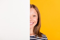 Portrait of charming positive young lady covering half face empty space wall isolated on yellow color background