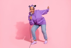 Photo of beautiful funky afro woman wear purple hoodie buns dancing singing karaoke smiling isolated pink color background