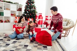 Photo of cute funny husband wife two children wear christmas sweaters sitting under tree waiting presents smiling indoors room home house