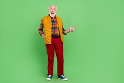 Photo of charming impressed senior gentleman wear yellow vest pointing finger empty space smiling isolated green color background