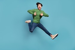 Full length photo of brunette amazed happy man jump make thumb up run sale wear jeans isolated on blue color background