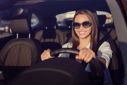 Photo portrait smiling woman wearing sunglass keeping steering wheel in the car