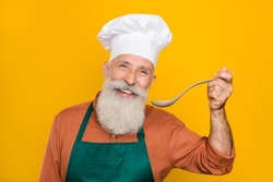 Portrait of attractive cheerful funny grey-haired man chef preparing meal fast food service isolated over bright yellow color background