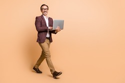 Full length body size view of attractive cheerful skilled man going using laptop copy empty space isolated over beige color background