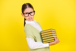 Profile side portrait of attractive girlish mad annoyed girl holding carrying book isolated over bright yellow color background