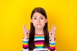 Photo of nervous small lady crossed fingers bite lip pray exam result wear striped shirt isolated yellow color background