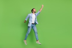 Full length profile side photo of young guy try to catch parasol look empty space jump isolated over green color background