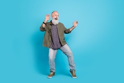 Full size photo of funky old man dance wearing khaki shirt jeans boots isolated over blue color background