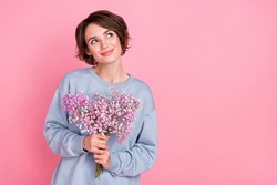 Portrait of attractive cheerful minded dreamy girl holding flowers copy space deciding isolated over pink pastel color background