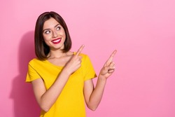 Photo of shiny charming young lady dressed yellow clothes smiling pointing two fingers empty space isolated pink color background