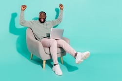 Full length body size view of handsome trendy cheery lucky guy using laptop rejoicing isolated over vivid teal turquoise color background