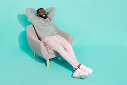 Full length body size view of attractive cheery dreamy guy sitting in armchair resting isolated over bright teal turquoise color background