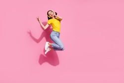 Photo of sweet dreamy young woman wear yellow outfit jumping high listening songs headphones empty space isolated pink color background