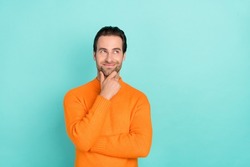 Photo of young man good mood hand touch chin curious look empty space isolated over teal color background