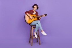 Full length photo of nice millennial brunette lady play guitar wear shirt jeans sneakers isolated on purple color background