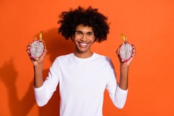 Photo of sweet funny guy dressed white shirt smiling holding tropical fruit isolated orange color background