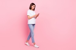 Full length body size view of attractive cheerful girl going using device browsing web isolated over pink pastel color background