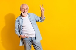 Portrait of attractive funky cheerful grey-haired man showing v-sign good mood isolated over bright yellow color background