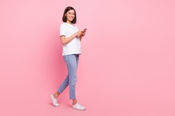 Full length body size view of attractive cheerful girl going using gadget web smm media multimedia isolated over pink pastel color background
