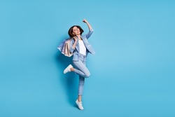 Photo of excited lucky woman wear jeans shirt rising fist bargains jumping high isolated blue color background