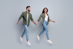 Full length photo of guy lady married couple jump go boutique center hold hand isolated over grey color background