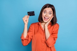 Portrait of attractive cheerful amazed girl holding in hand bank card nfc method great news isolated over bright blue color background